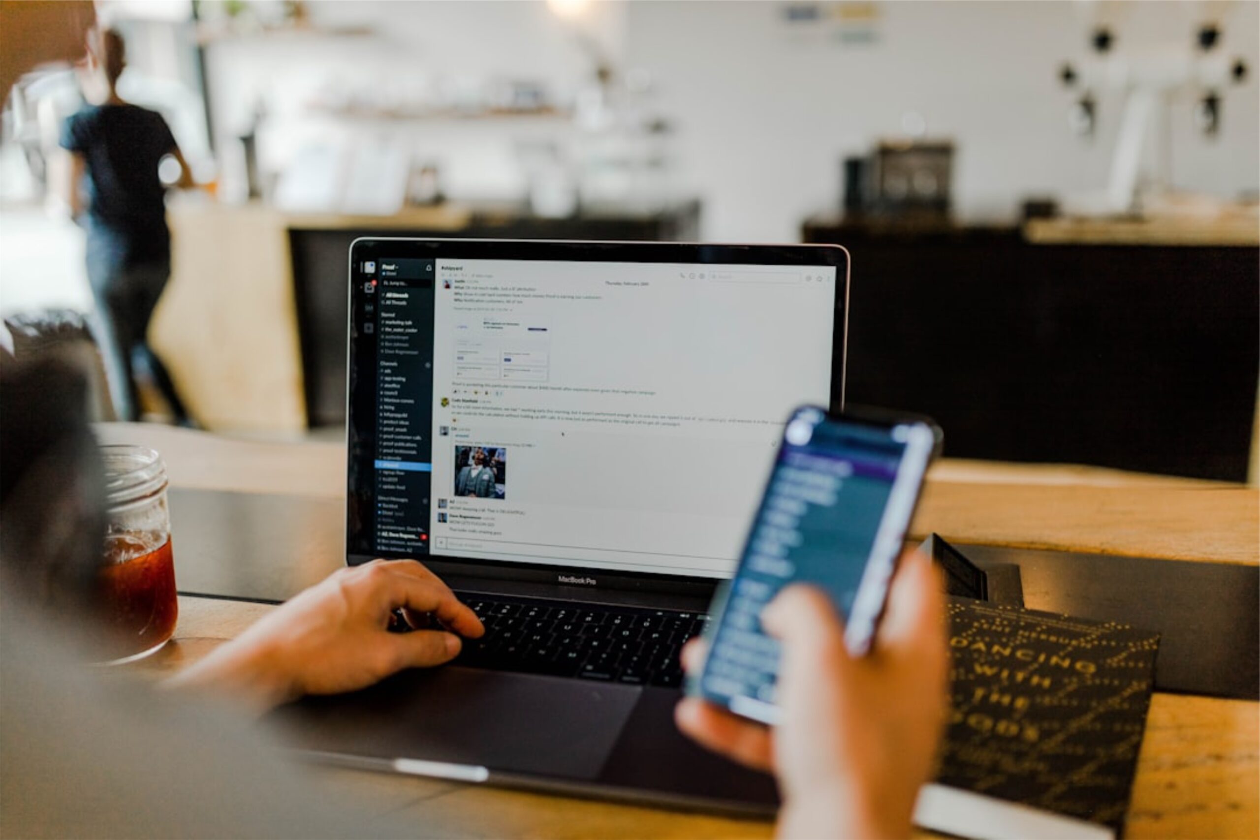Person holding a phone while typing on the computer